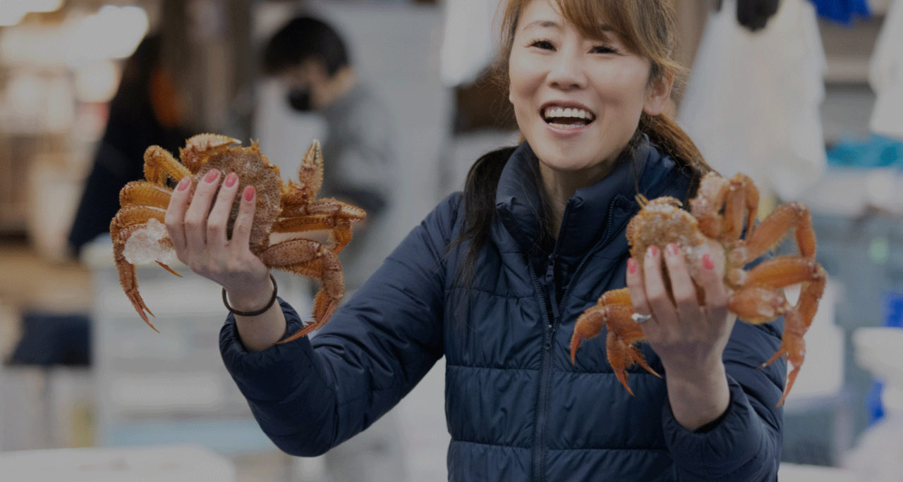 蟹を両手に持つ笑顔の女性