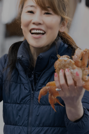 蟹を両手に持つ笑顔の女性